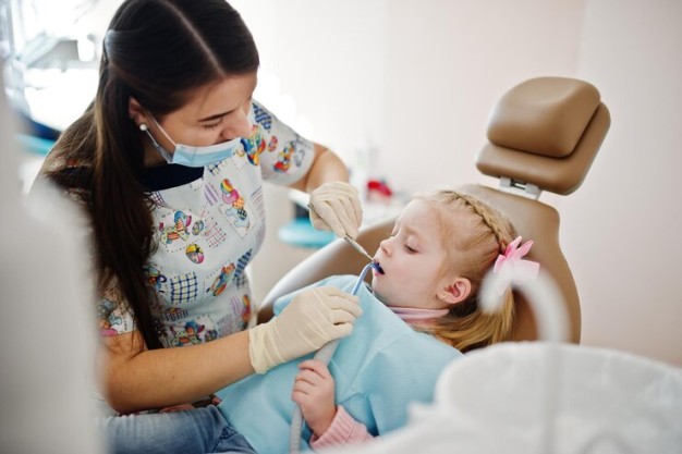 Pediatric dentist performing dental checkup on a child